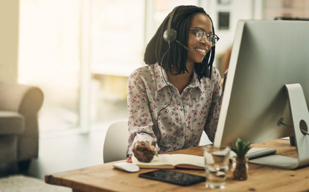 A woman wearing a headset while sitting at a computer.