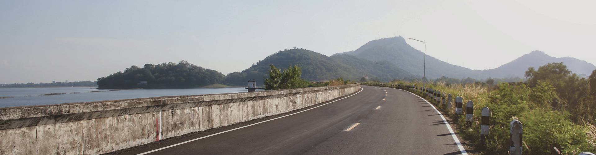 Long-shot photograph of a coastal highway curving into distant hills.